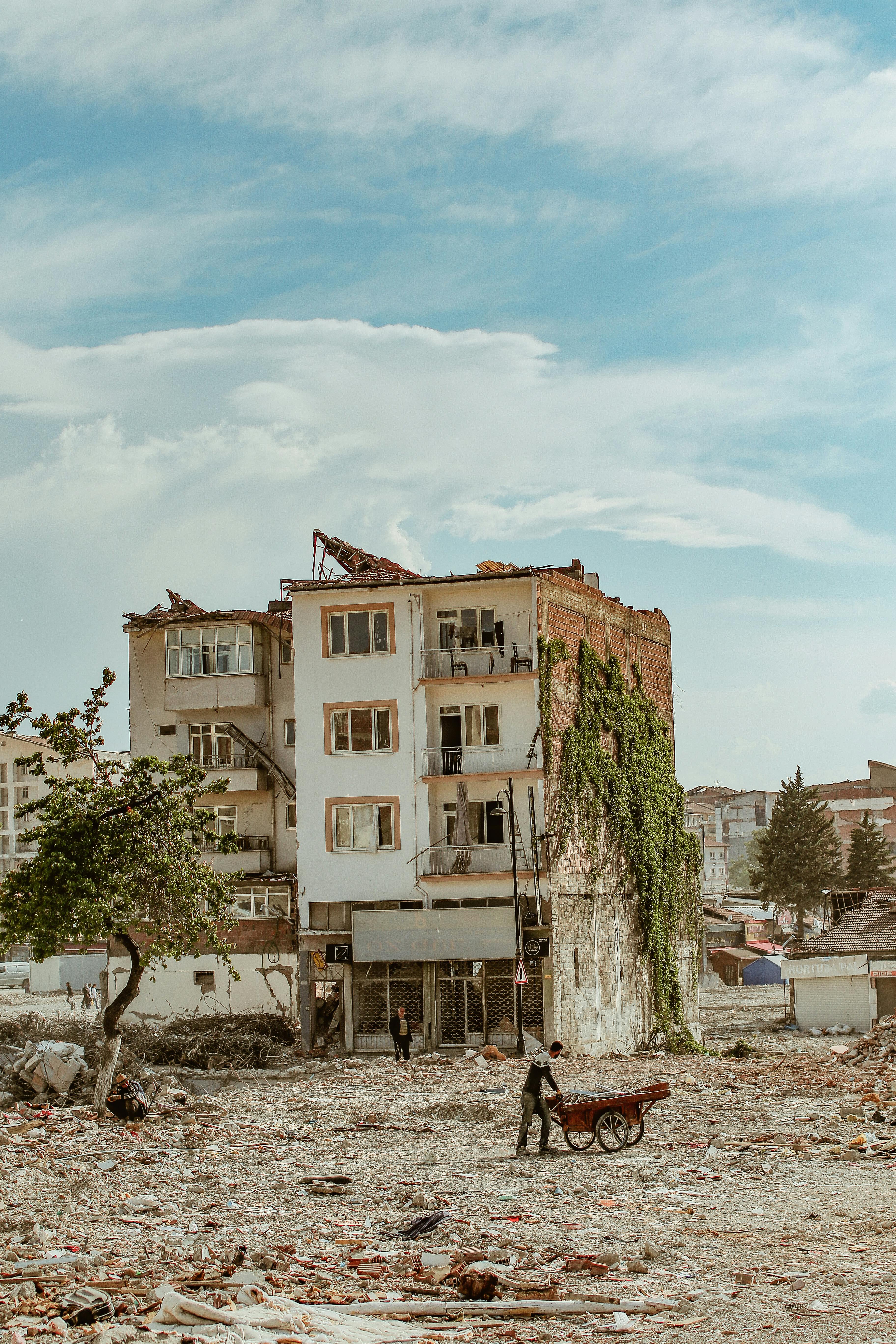 A damaged building in an urban area surrounded by rubble and debris, signifying abandonment.