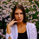 一位女性在盛开的雏菊背景下摆出特写肖像，散发着自然之美与宁静