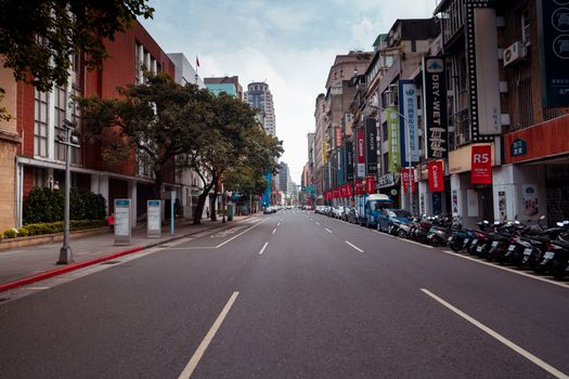 A bustling urban street in Taipei, Taiwan, lined with modern buildings and vibrant signage, showcasing city life.
