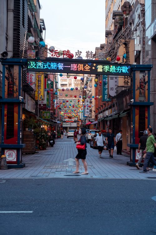 Free Vibrant market street scene in Taiwan with pedestrians and colorful signage, capturing urban life. Stock Photo