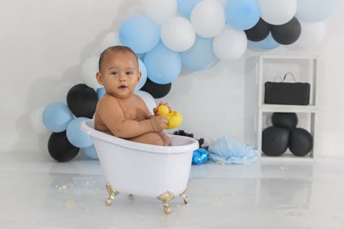 Free A Little Boy in a Tiny Bathtub on the Background of Balloons  Stock Photo