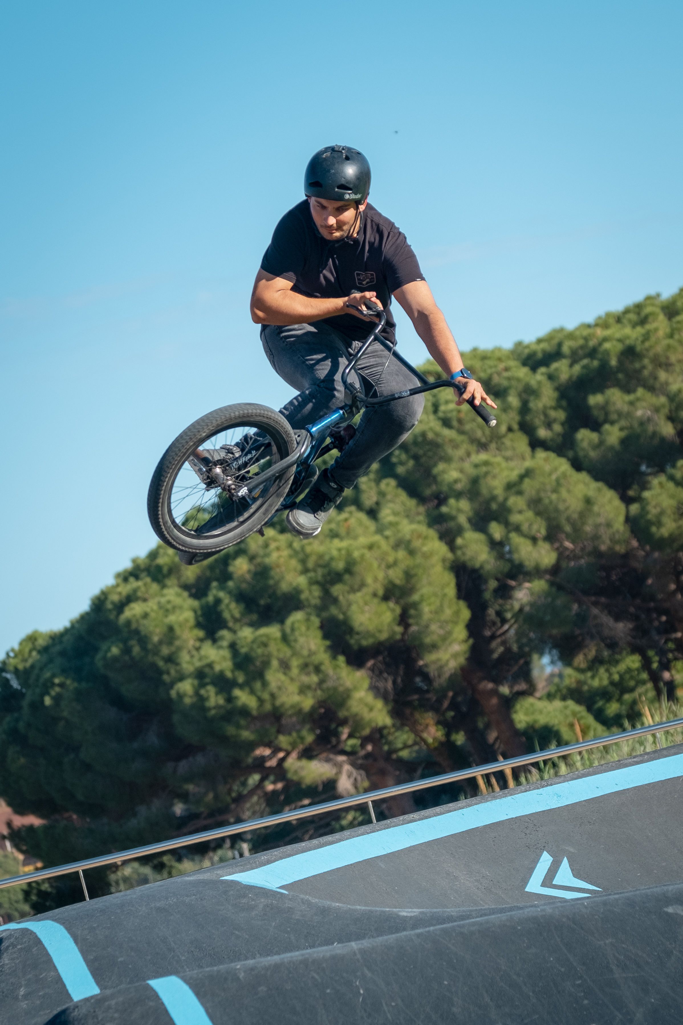 A BMX cyclist performs an aerial stunt outdoors at a park, capturing the thrill of motion.