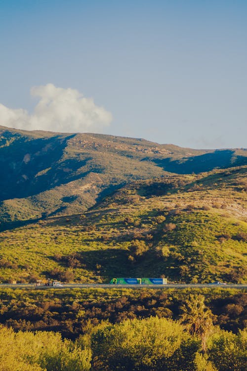 A Truck on an Asphalt Road in Mountains seen from Distance 