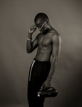 Black and white portrait of a stylish young man with eyeglasses and a speaker.