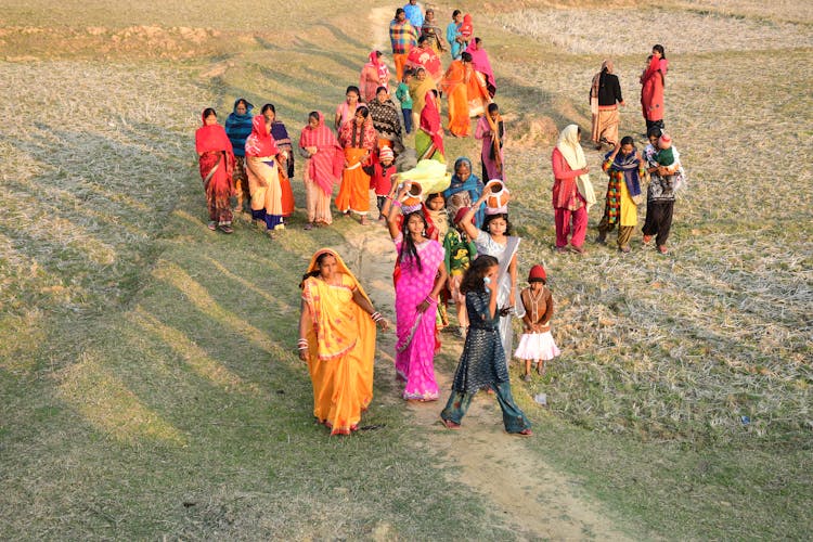 High Angle Shot Of A Group Of Women In Traditional Dresses Walking On A Field 