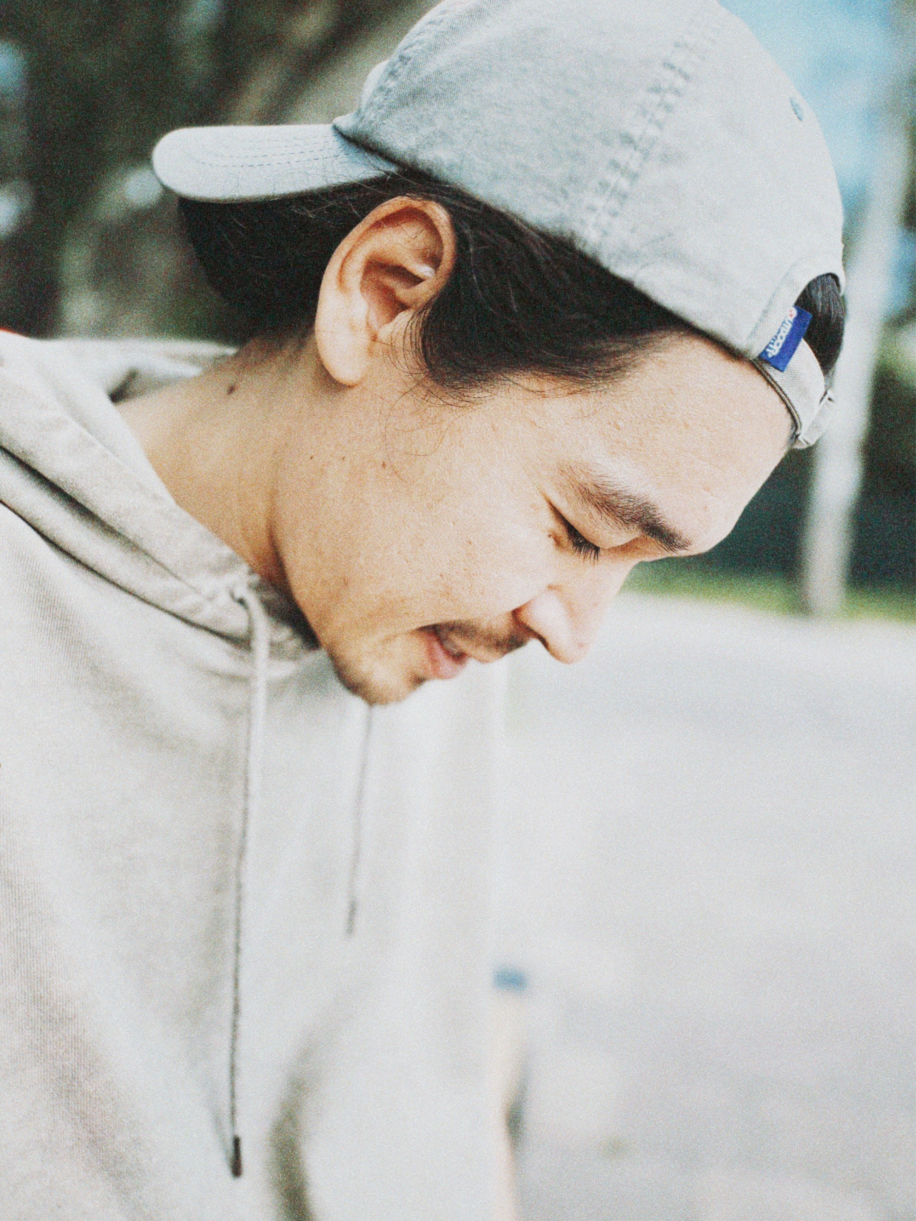 A candid portrait of a man wearing a hoodie and cap, outdoors in Almaty, Kazakhstan.