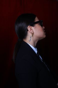 Side view of an elegant woman in a suit and sunglasses, captured in a studio setting.