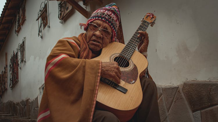 Elderly Man In Traditional Clothing Playing The Guitar 