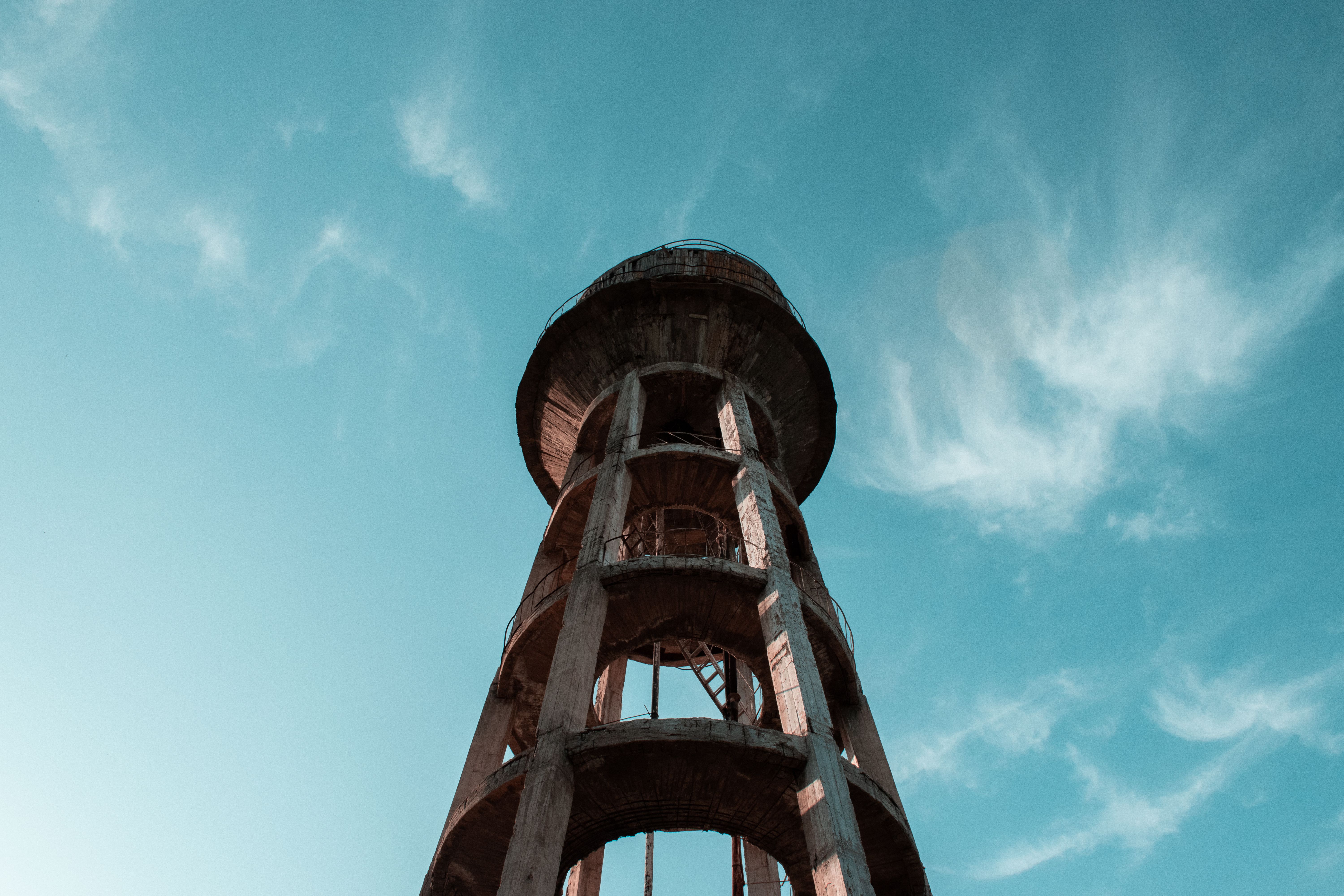Low angle view of a historic tower in Alişar, Türkiye against a bright blue sky.
