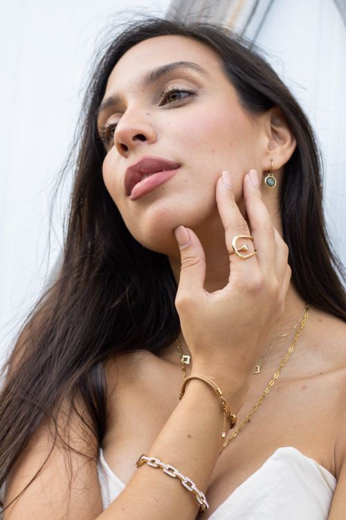 Free A young woman poses gracefully, showcasing elegant gold jewelry outdoors. Stock Photo