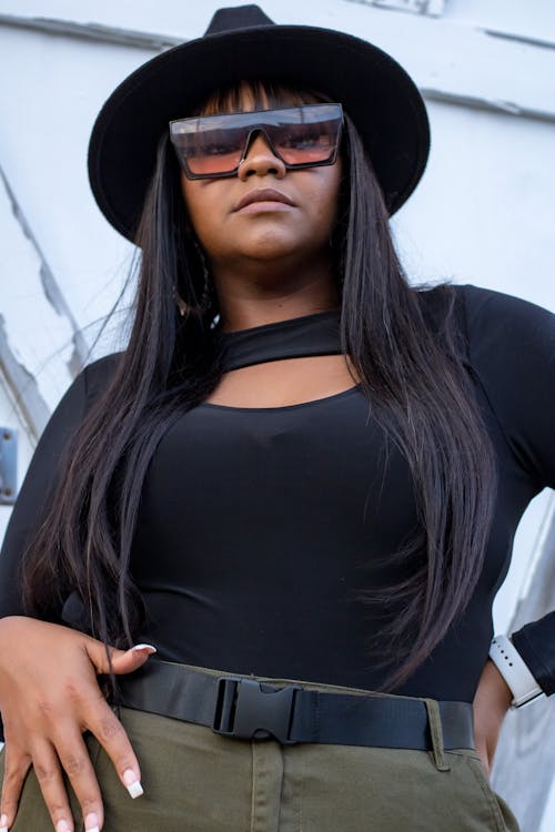 Young Brunette Woman Posing in Black Blouse, Fedora Hat, and Sunglasses