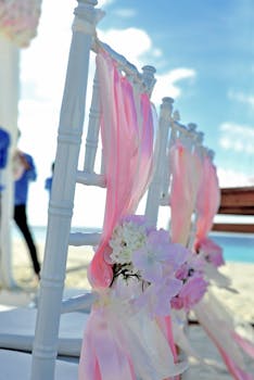 在一个宁静的马尔代夫海滩婚礼上，白色椅子搭配着粉红色丝带