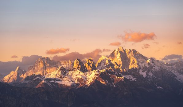 A breathtaking view of the Dolomites at sunset, showcasing a warm golden hue and snow-capped peaks.