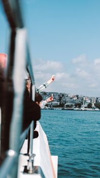 Visitors enjoy the scenic view from a cruise ship as it travels near a coastal city skyline.