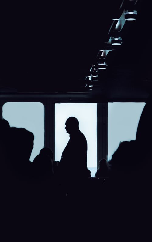 Free Elegant silhouette of a man against large windows in a modern interior, evoking mystery and thought. Stock Photo