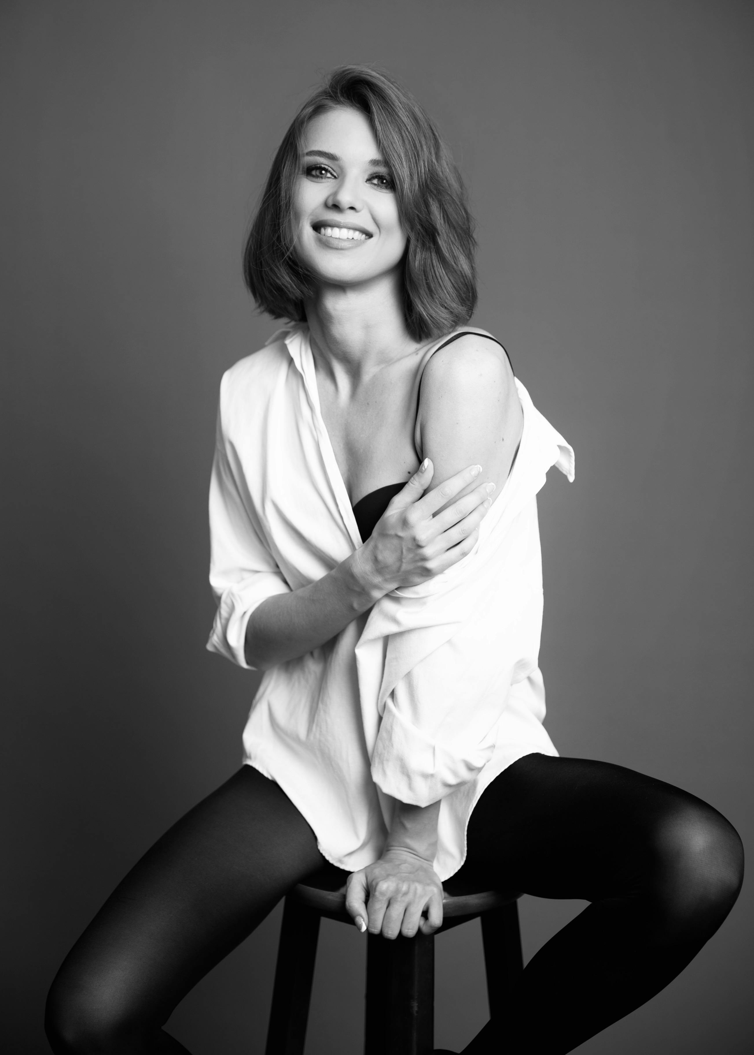 Black and white portrait of a woman posing in a studio setting, exuding elegance and charm.