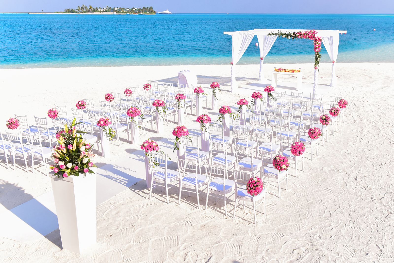 Simple beach ceremony setting with white chairs and open shoreline.