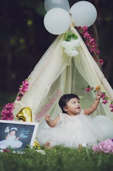Adorable baby girl celebrates her first birthday outdoors with a tent and floral decorations.