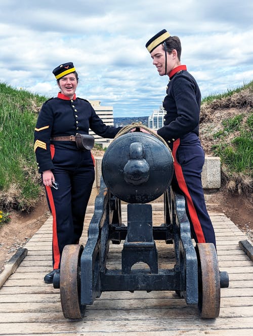 Man and Woman in Uniforms Standing with Cannon