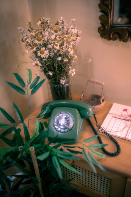 A Vintage Telephone Standing on a Dresser next to a Bunch of Wildflowers