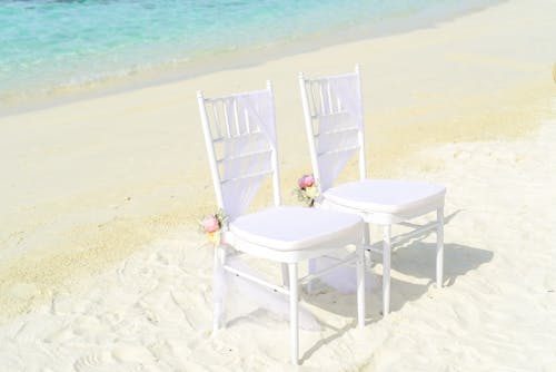 Два белых безруких кресла на берегу моря