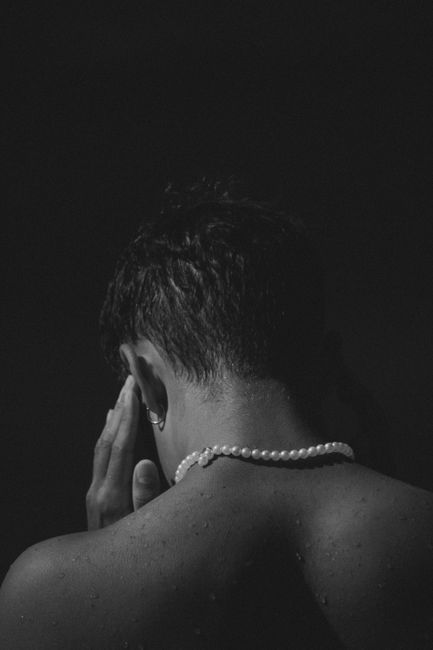 Elegant black and white portrait of a man with pearls, focusing on artistic expression.