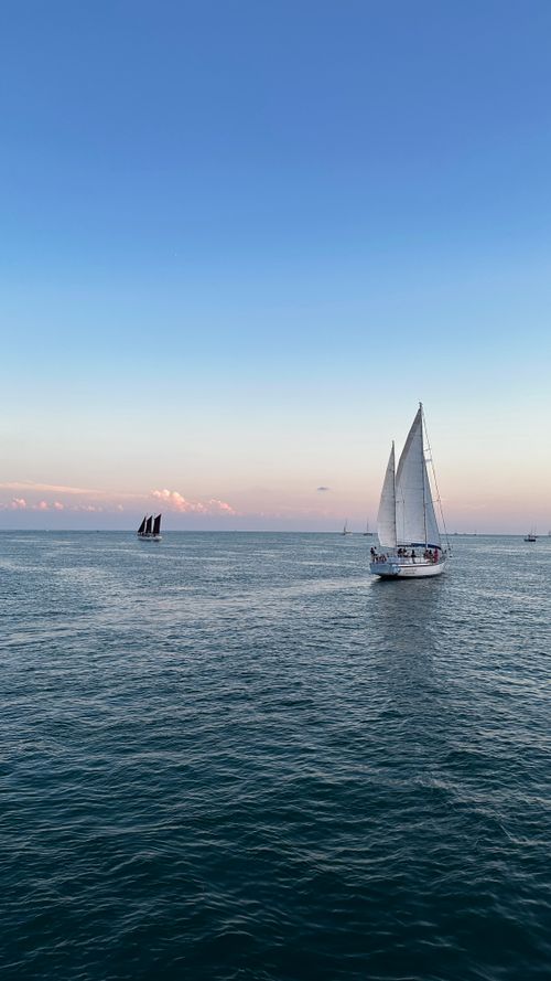 Free A serene scene of a sailboat on calm ocean waters during sunset, capturing the beauty of sailing. Stock Photo