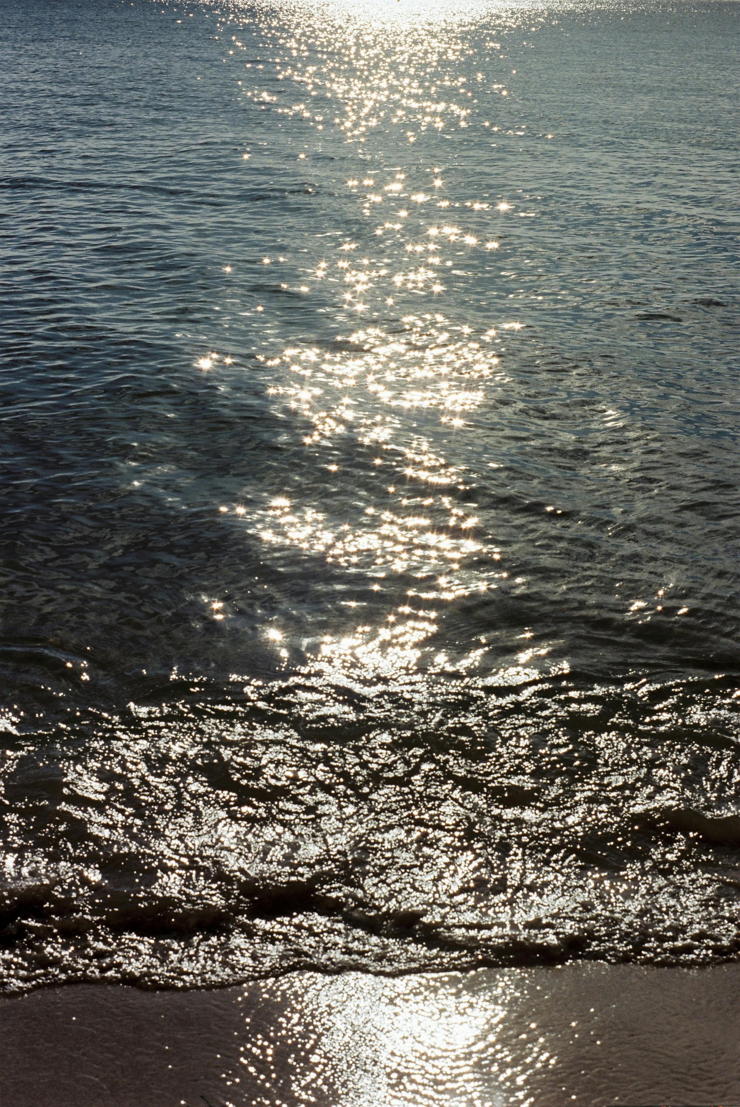 A mesmerizing view of sunlight reflecting off the waves on a Vietnamese shoreline, creating a sparkling effect.