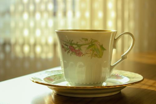 Free Close-up of a beautiful porcelain teacup on a table, lit by warm sunlight. Stock Photo