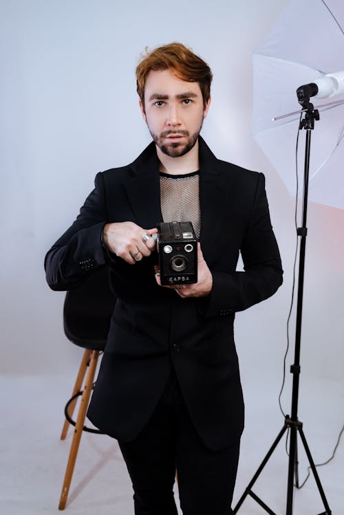 Man in Black Suit Standing with Vintage Camera