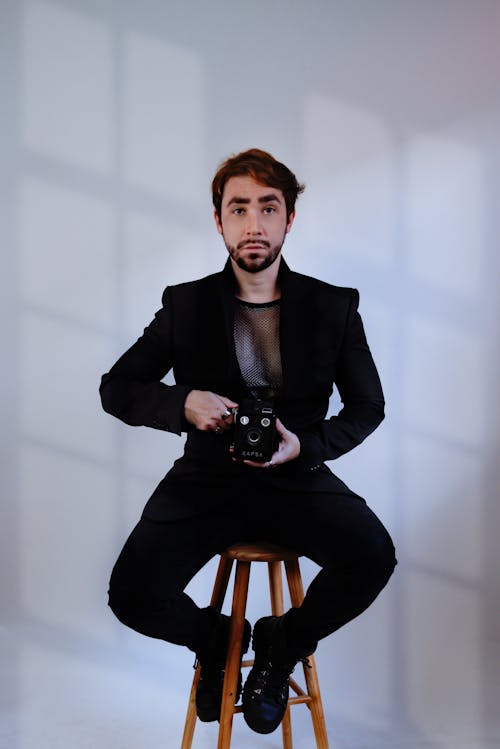 Man in Black Suit Sitting with Camera