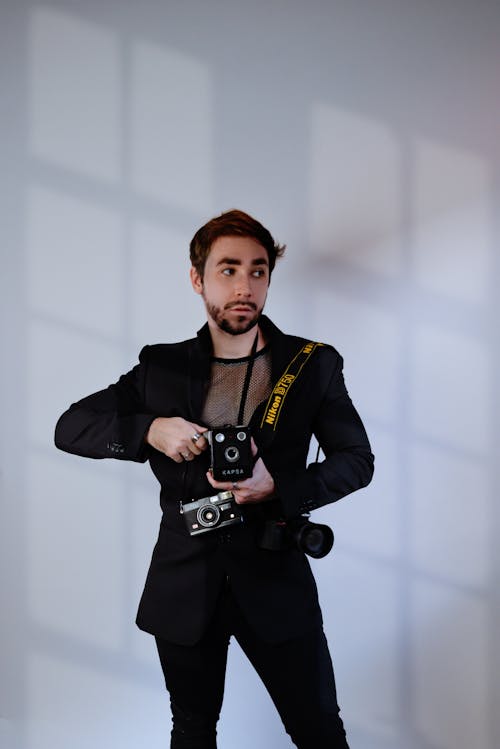 Man in Black Suit Standing with Cameras