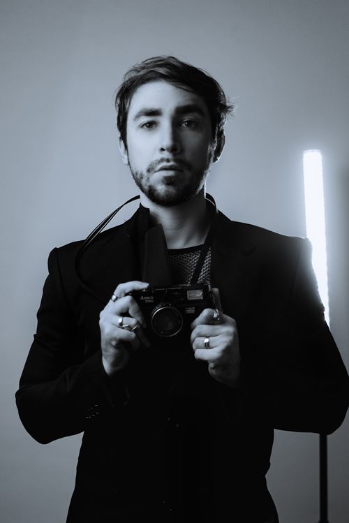 Free Artistic black and white portrait of a man holding a camera with dramatic lighting. Stock Photo