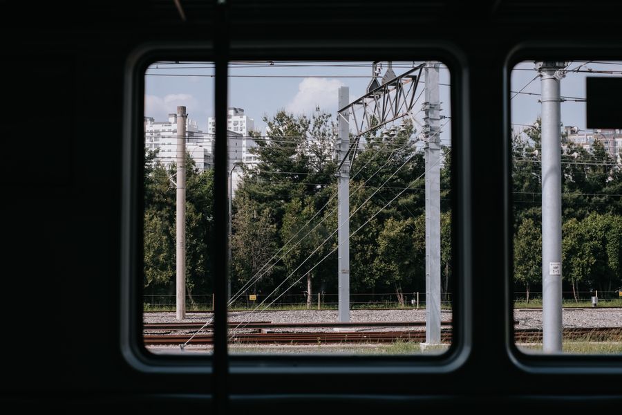 Urban view captured from a train window in Chuncheon, showcasing tracks and city buildings.