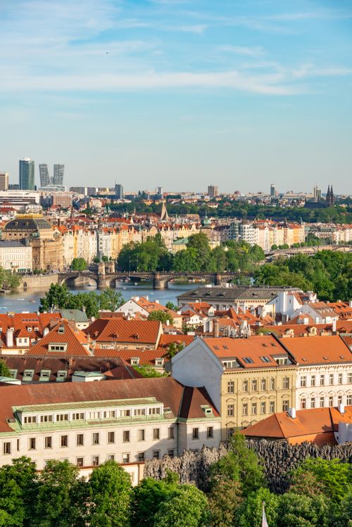 Free A stunning aerial view of historic Prague with red rooftops and lush greenery under a clear blue sky. Stock Photo