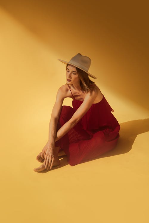 Woman in a Dress and a Hat Sitting on the Ground