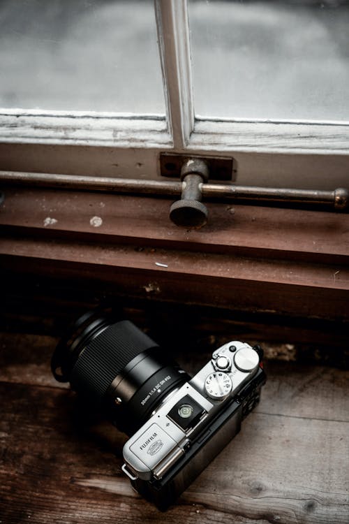 A camera sitting on a window sill next to a window