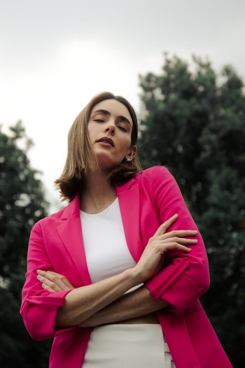 Young Woman in a Pink Blazer Standing Outside with Eyes Closed 