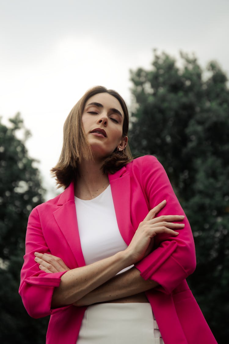 Young Woman In A Pink Blazer Standing Outside With Eyes Closed 