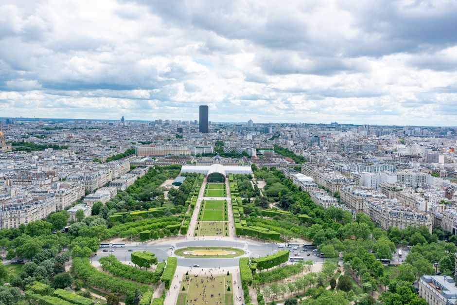 Aerial shot of Champ de Mars with panoramic view of Paris under cloudy skies.