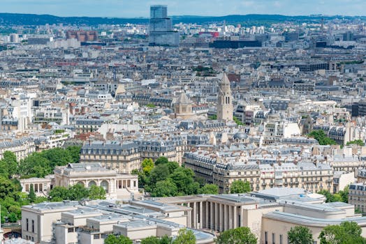 An aerial view of Paris showcasing the city's iconic architecture and landmarks on a bright day.