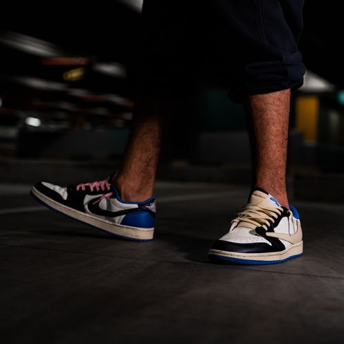 Free Fashion-forward sneakers captured on a man's feet in a dimly lit setting, showcasing streetwear style. Stock Photo