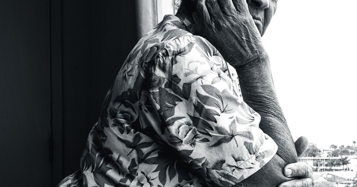 Black and white portrait of an older woman looking thoughtfully out a window