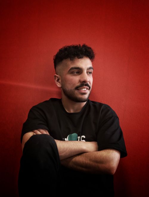 Free Young man with mustache in black t-shirt smiling in a studio with a red background. Stock Photo