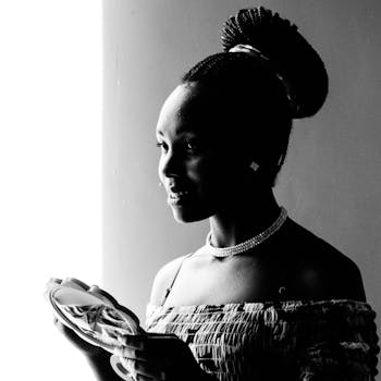 一幅黑白肖像中，一位微笑的女人编着辫子，手拿一面镜子