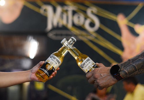 Close-up of Two People Clinking Beer Bottles