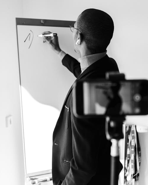 Man Recording Himself Writing on Whiteboard
