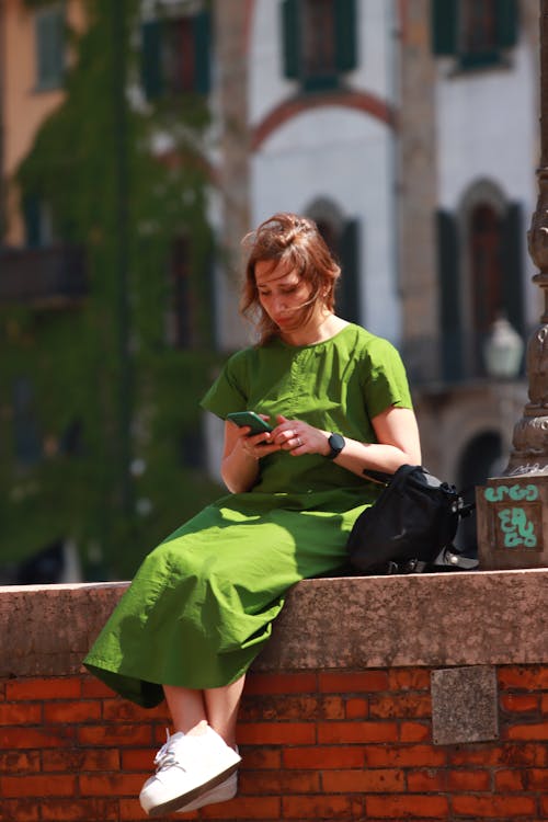 Woman in Green Dress Sitting on Wall