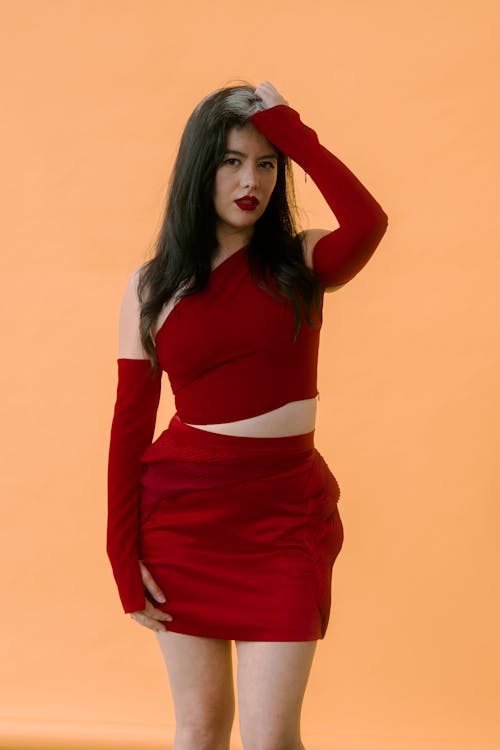 Studio Shot of a Young Woman in a Red Dress Fixing Her Hair 