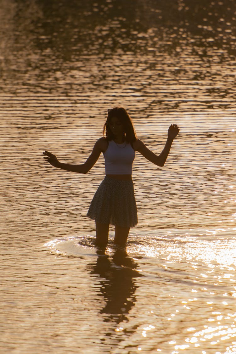 Woman In Skirt In Lake At Sunset